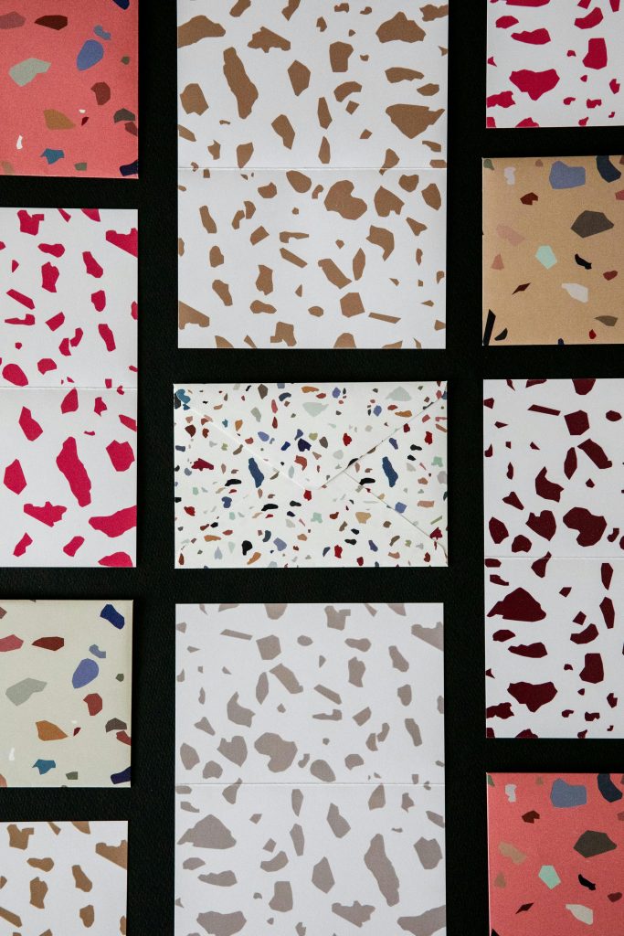 Modern terrazzo pattern design with multicolored speckles and abstract shapes.