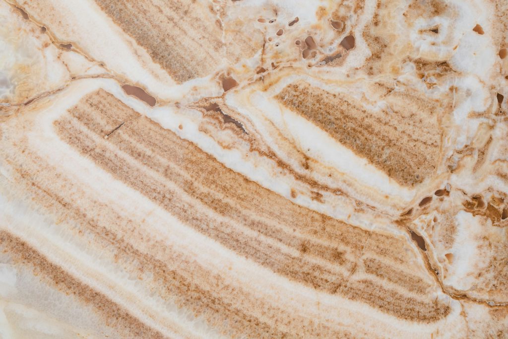 Detailed close-up of brown and white marble texture, showcasing natural cracks and patterns.