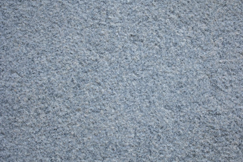 Detailed close-up texture of a rough concrete pavement, showcasing its unique surface pattern.